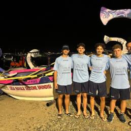 Cinque giovani della Lega Navale Brindisi sulla spiaggia accanto alla barca ai Tesori del Mediterraneo 2026 a Reggio Calabria
